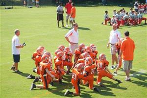 A youth football team kneeling with coaches